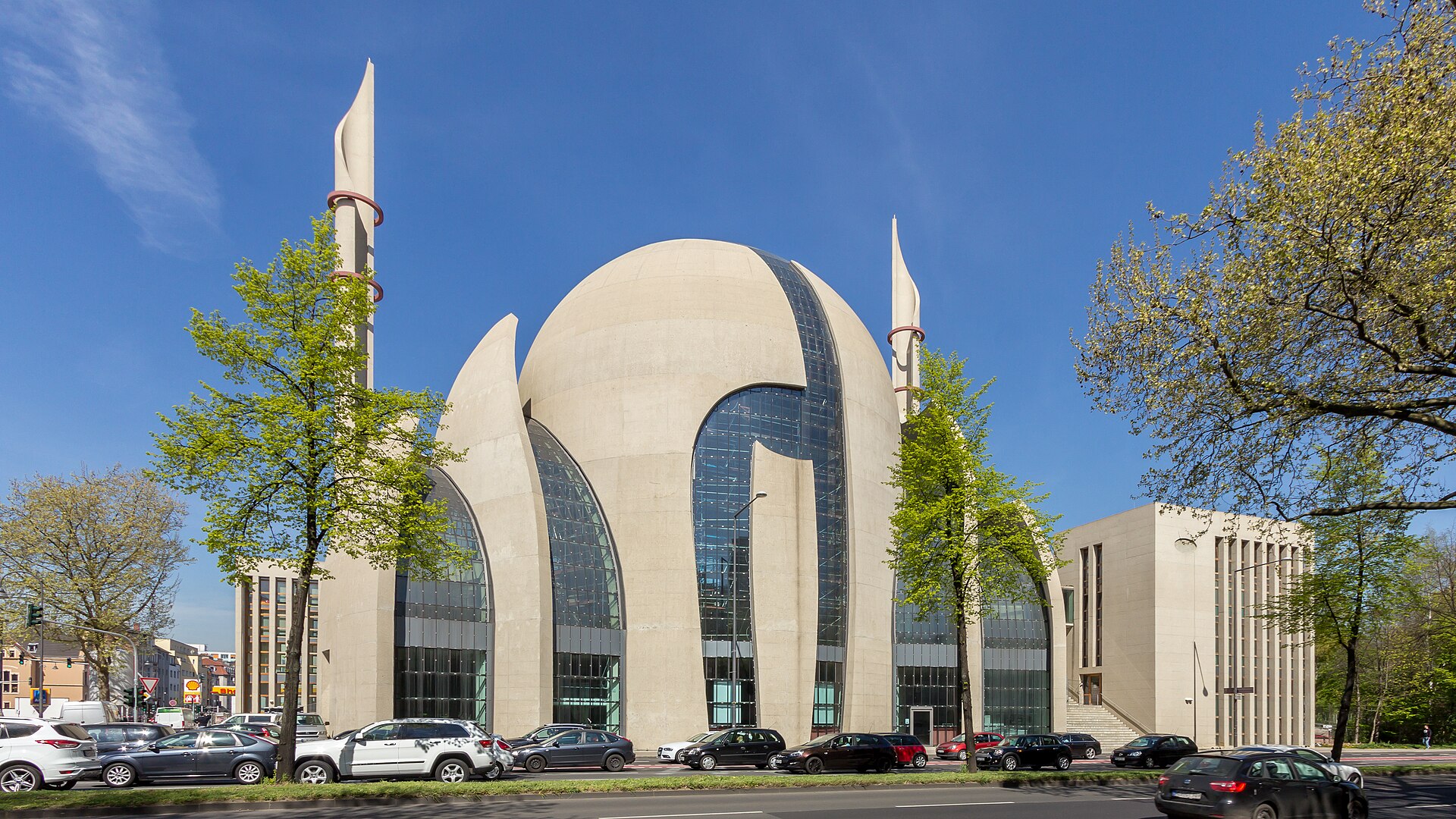 Die DITIB-Zentralmoschee in Köln von außen, Kuppel und zwei Minarette vor blauem Himmel