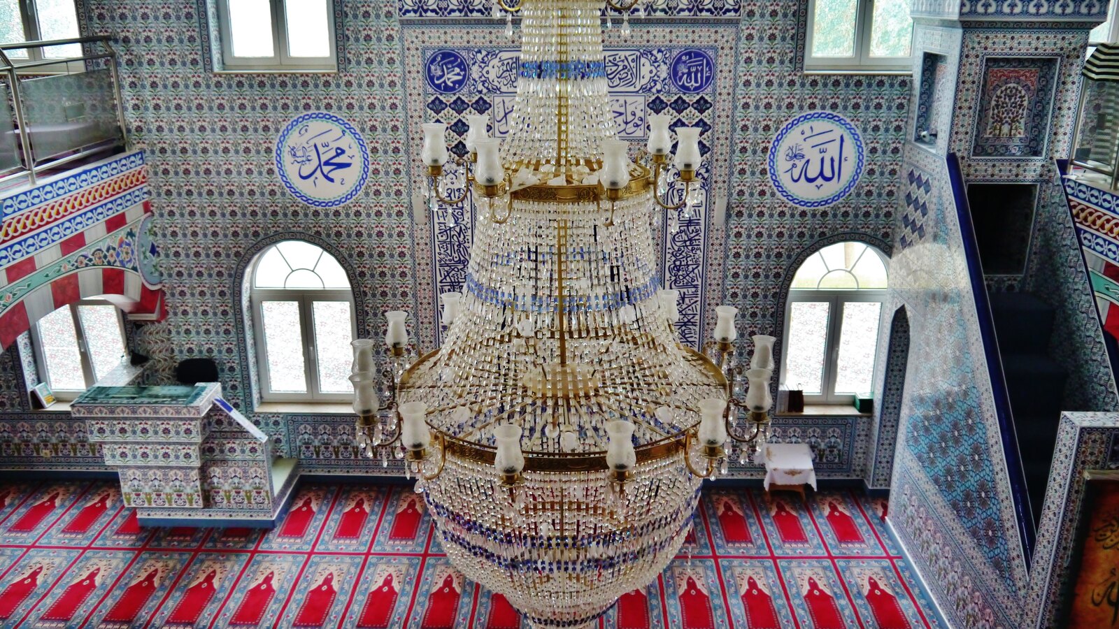 Der Gebetsraum der Centrum-Moschee in Rendsburg mit Kronleuchter, Fliesenmosaik und rotem Gebetsteppich