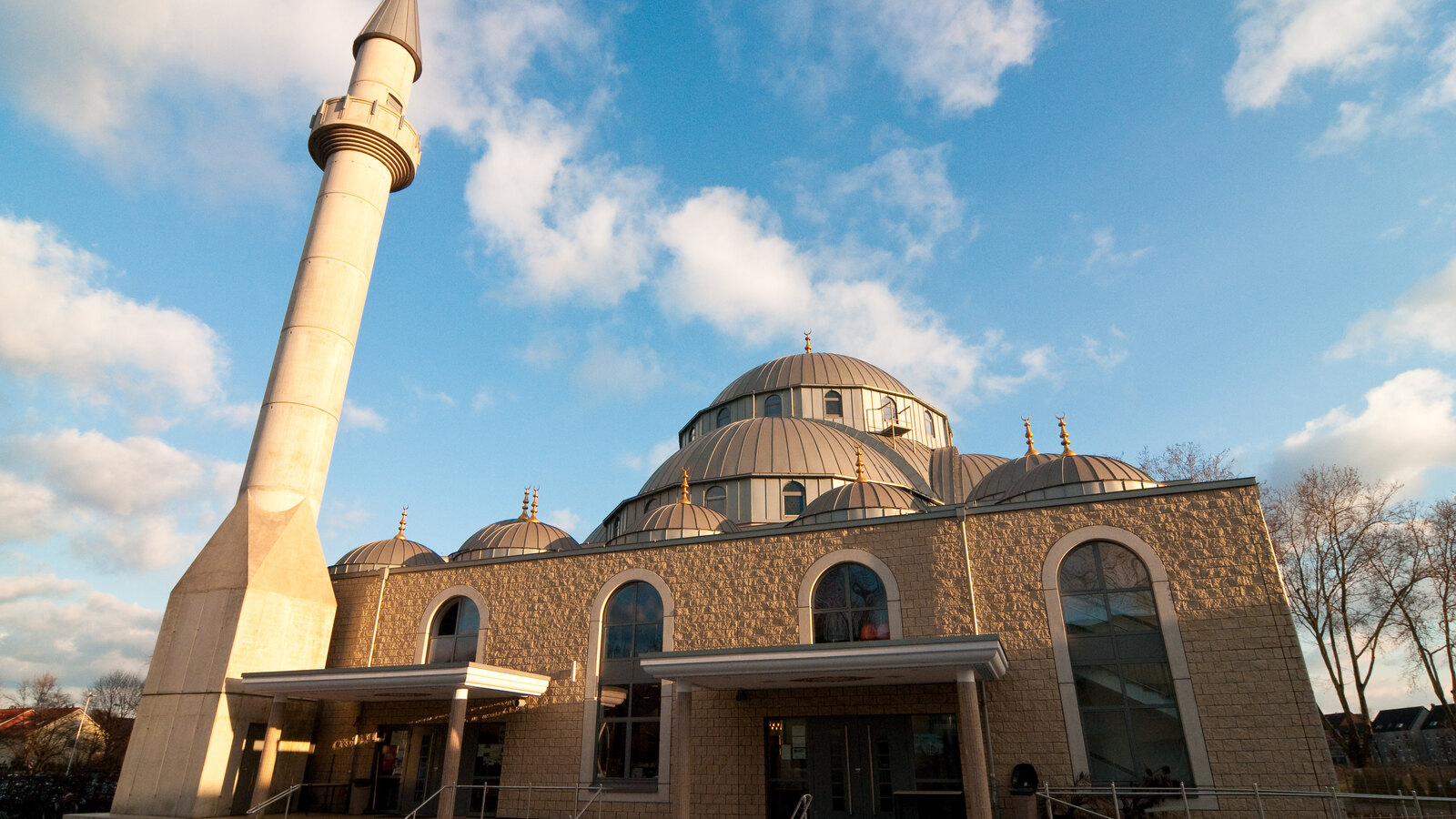 Die Merkez-Moschee in Duisburg-Marxloh im Abendlicht, mit Minarett, Kuppeln und Vorplatz